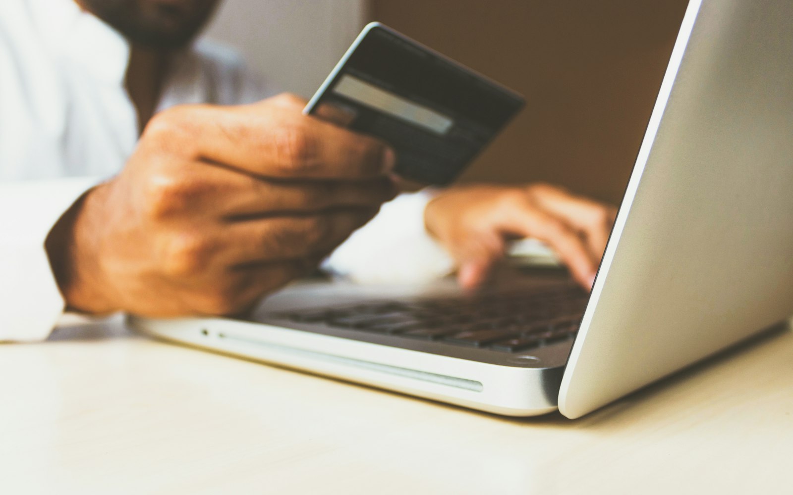 Person entering card details on a laptop, representing faster WooCommerce checkout performance
